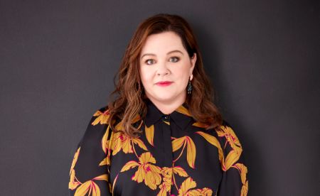 Actress Melissa McCarthy in a black dress poses at a photoshoot.